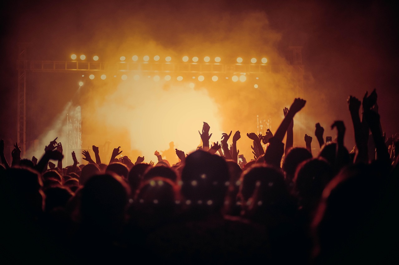 Gran multitud en un concierto con las luces del escenario al fondo